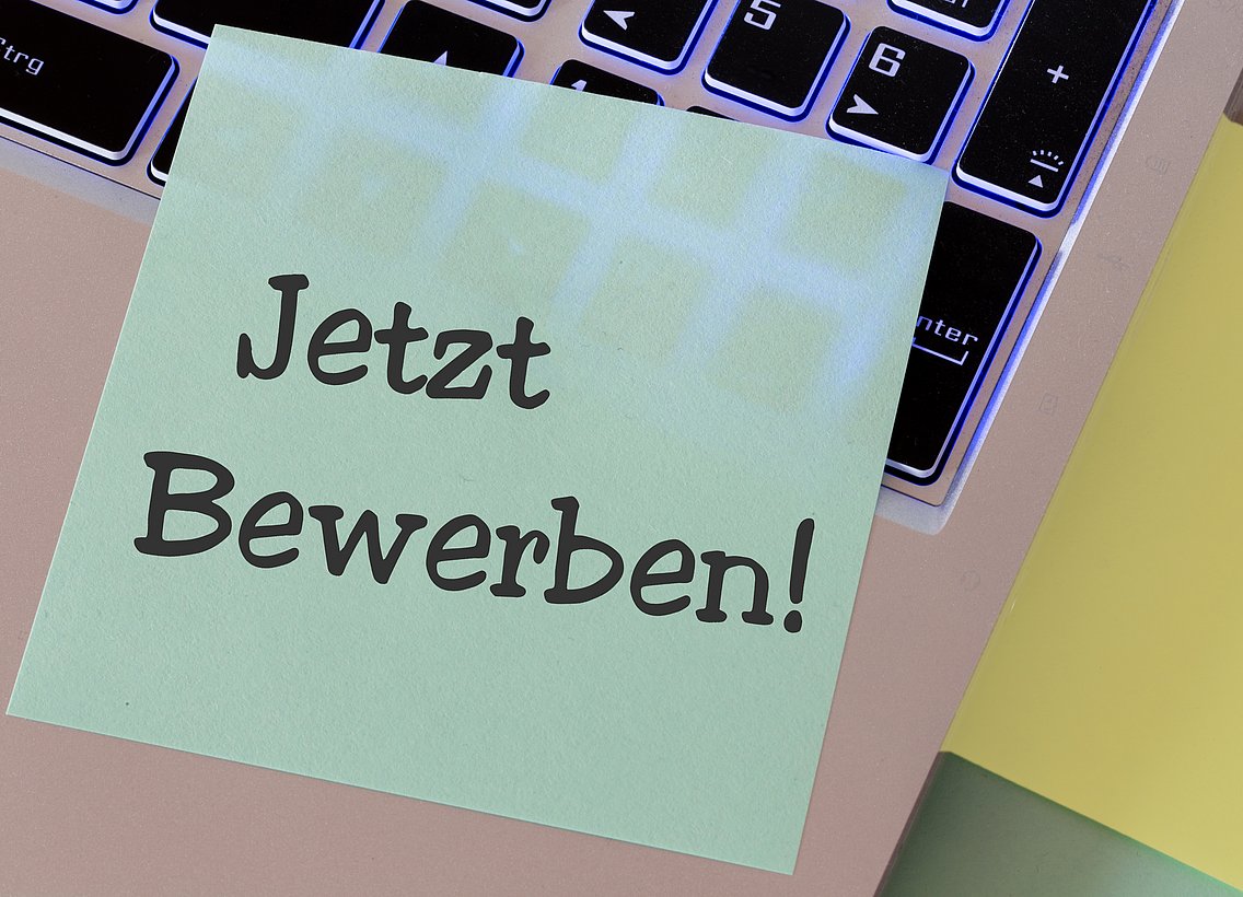 Ein Post-It mit der Aufschrift Jetzt Bewerben klebt auf einer Laptoptastatur